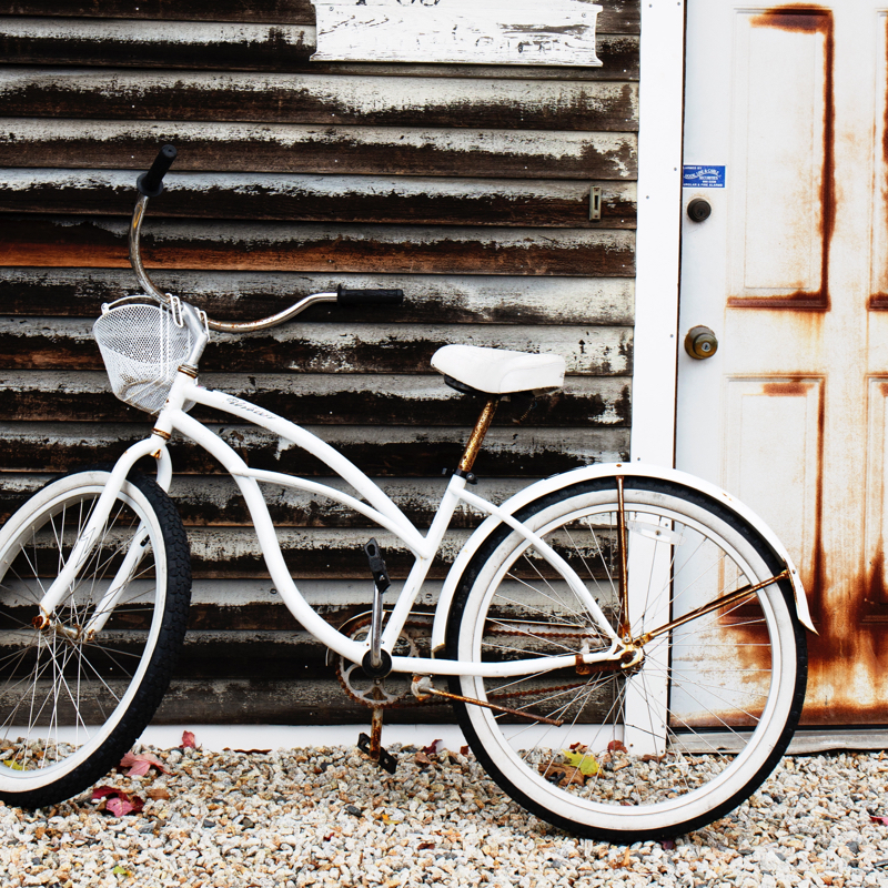 an old-fashioned Schwinn-style bicycle leaning against a rusty house