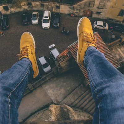 feet dangling over a building wearing casual sneakers